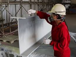 Coating inspector at work on a West African industrial site — over-the-shoulder framing, no visible face, clipboard and thickness gauge in hand